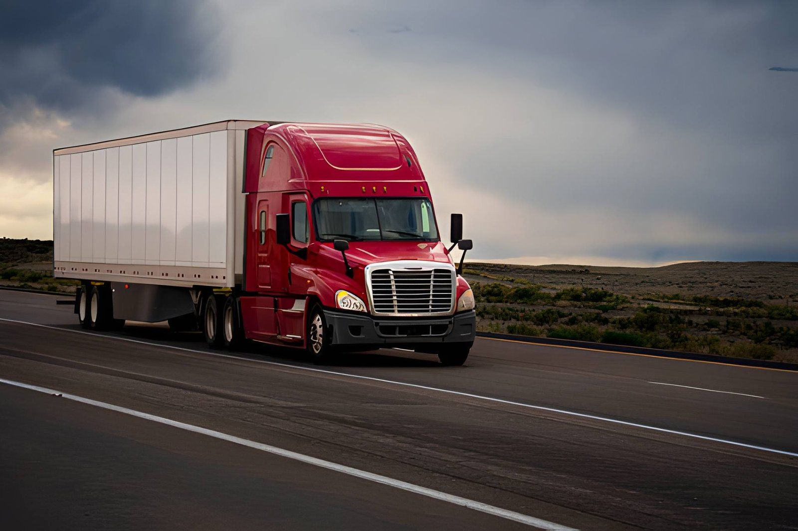 Red Heroic Solutions semi truck hauling a dry van trailer on an open highway at dusk